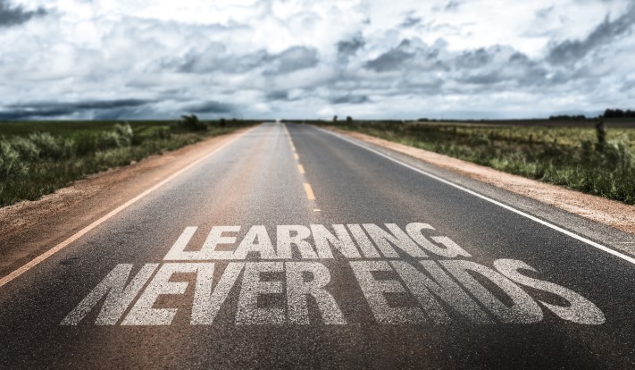 Road with 'Learning Never Ends' written on it, stretching into the horizon, symbolizing continuous professional development and mentoring